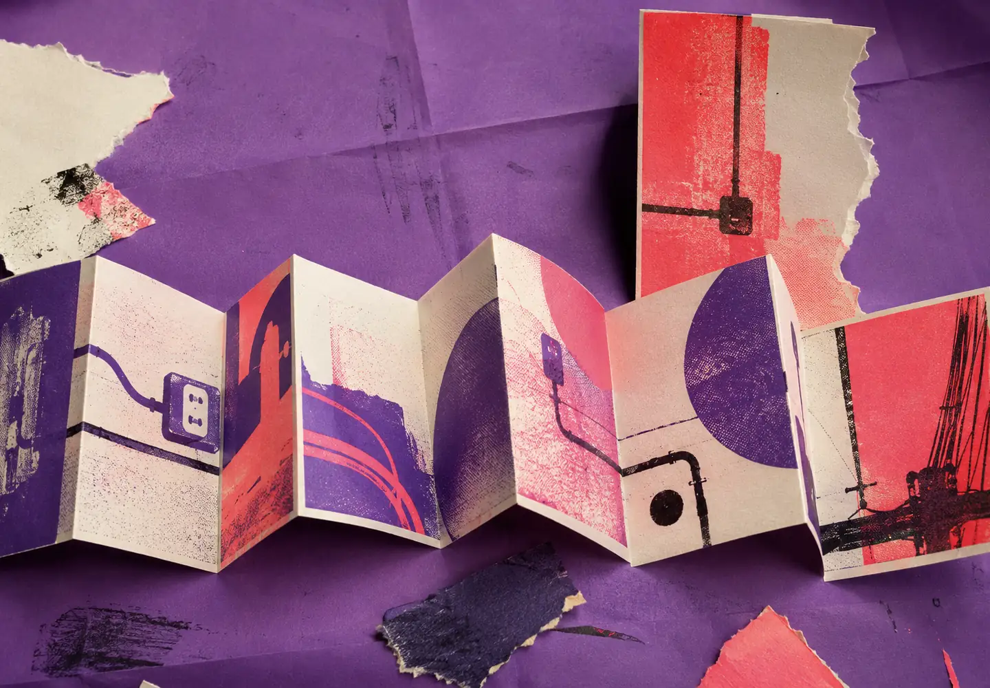 Acordeón de papel impreso en coral y violeta con siluetas abstractas de conducciones y tomas